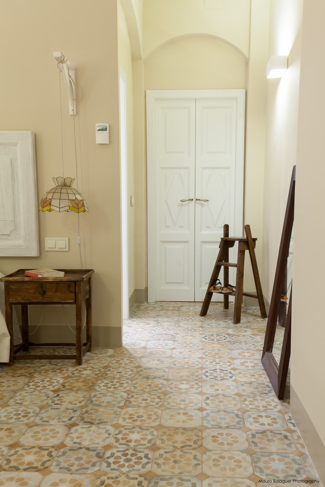 Esempio di un ingresso mediterraneo di medie dimensioni con pareti beige, pavimento con piastrelle in ceramica, una porta a due ante e una porta bianca
