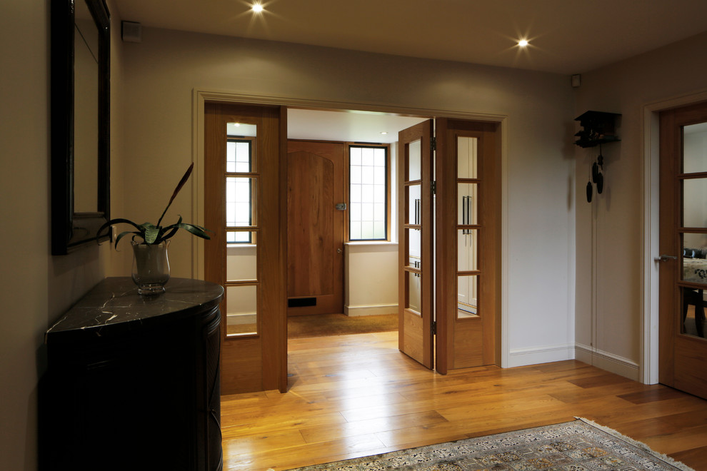 Idee per una grande porta d'ingresso tradizionale con pareti grigie, pavimento in legno massello medio, una porta singola, una porta in legno bruno e pavimento marrone