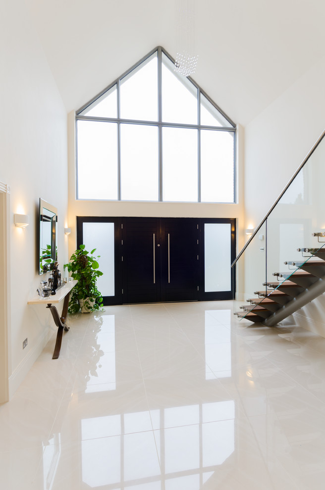 Пример оригинального дизайна: огромное фойе в современном стиле с белыми стенами, полом из керамической плитки, двустворчатой входной дверью и черной входной дверью