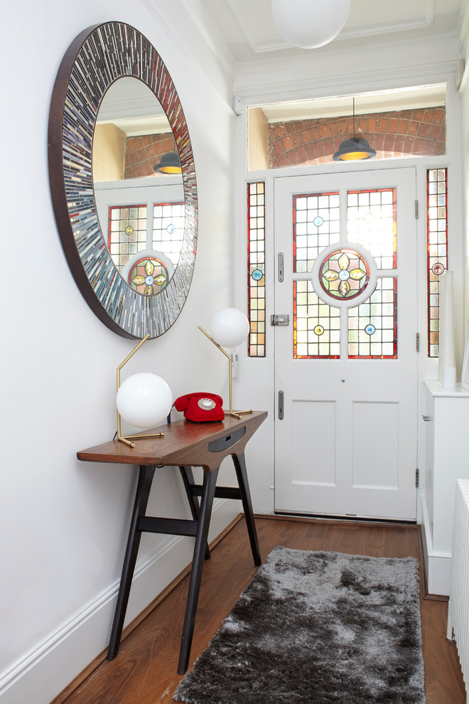 Stilmix Eingang mit Korridor, weißer Wandfarbe, dunklem Holzboden, Einzeltür und weißer Haustür in London