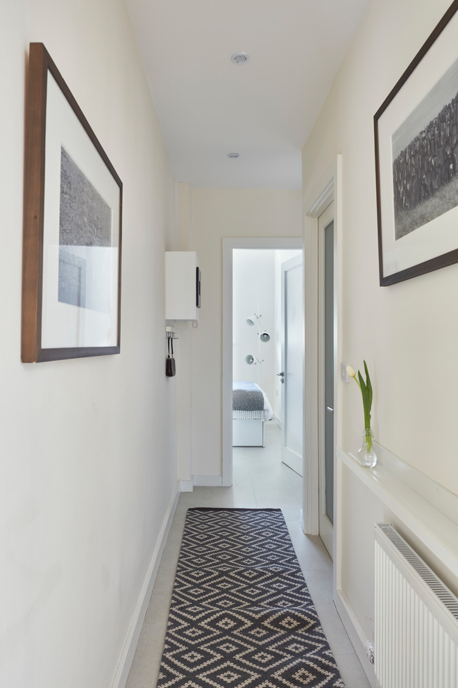 ダブリンにあるお手頃価格の中くらいな北欧スタイルのおしゃれな玄関ホール (白い壁、クッションフロア、木目調のドア、白い床) の写真