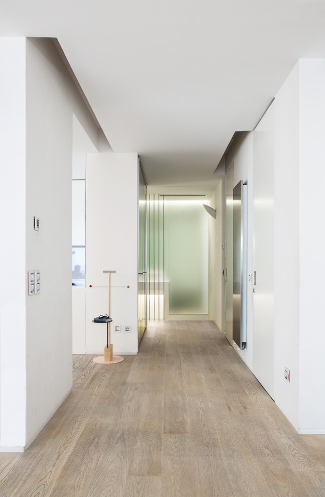This is an example of a large scandinavian foyer in Florence with white walls and light hardwood floors.