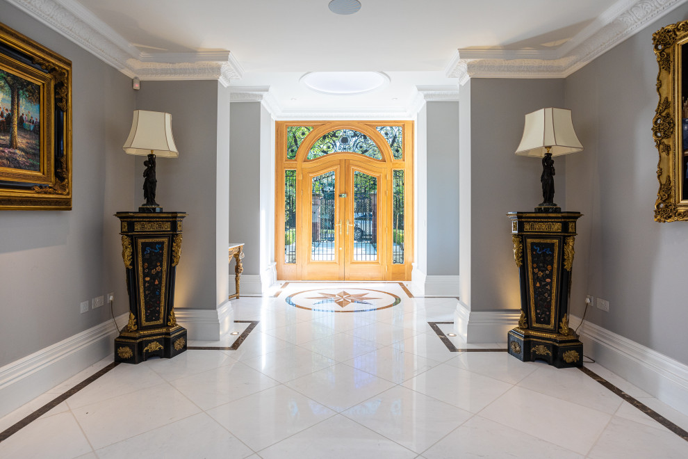 チェシャーにあるラグジュアリーな広いコンテンポラリースタイルのおしゃれな玄関ホール (グレーの壁、木目調のドア、白い床、大理石の床) の写真