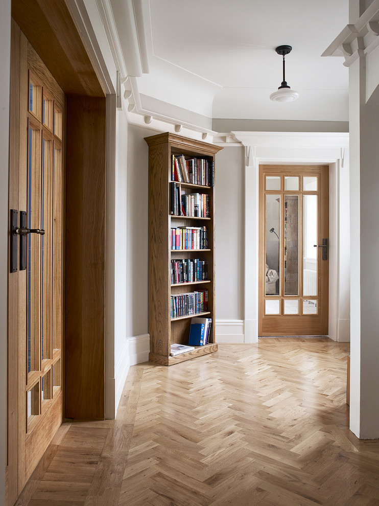 Klassisk inredning av en foajé, med grå väggar, ljust trägolv, en dubbeldörr, en grå dörr och beiget golv