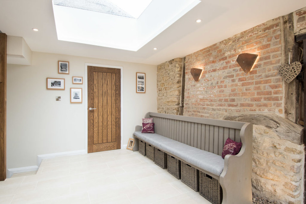 This is an example of a medium sized farmhouse entrance in Oxfordshire with beige walls, a single front door, a medium wood front door and beige floors.