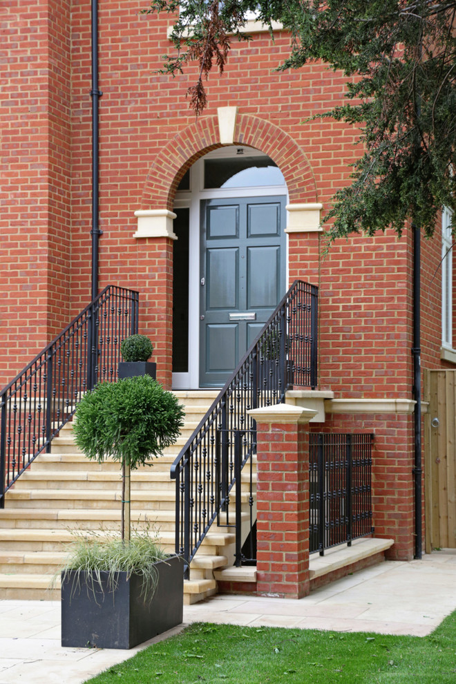 На фото: входная дверь в классическом стиле с красными стенами, одностворчатой входной дверью и черной входной дверью с