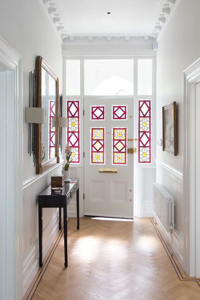 Design ideas for a traditional hallway in London with white walls, light hardwood flooring, a single front door, a glass front door and feature lighting.