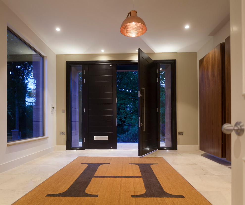 Idée de décoration pour une grande porte d'entrée design avec un mur vert, un sol en calcaire, une porte double et une porte noire.