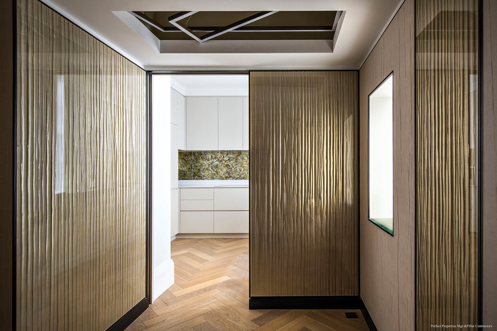 Ejemplo de vestíbulo actual pequeño con paredes metalizadas, suelo de madera clara y puerta simple