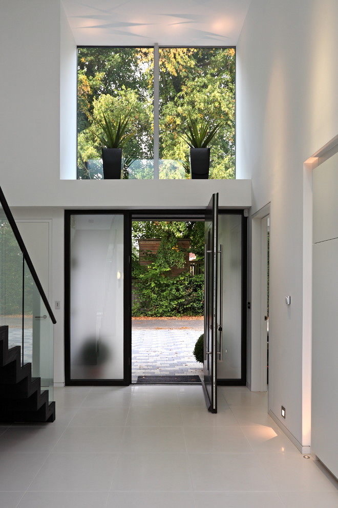 Inspiration pour un hall d'entrée design avec un mur blanc, une porte simple, une porte en verre et un sol blanc.