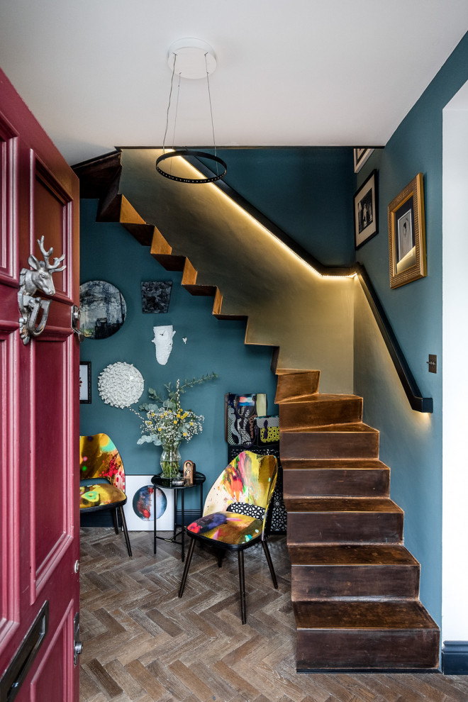 ロンドンにあるお手頃価格の小さなエクレクティックスタイルのおしゃれな玄関ホール (青い壁、無垢フローリング、赤いドア、茶色い床) の写真