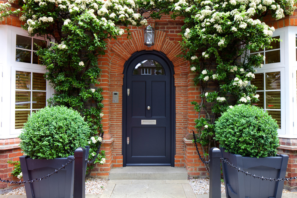 Klassische Haustür mit roter Wandfarbe, Betonboden, Einzeltür, schwarzer Haustür und grauem Boden in London