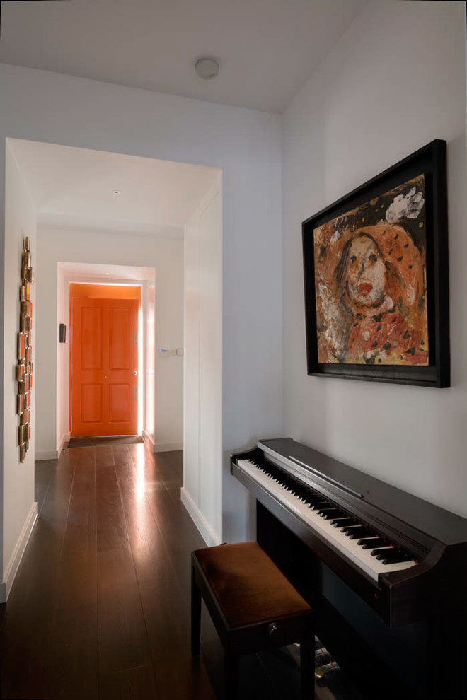 This is an example of a large contemporary front door in London with white walls, dark hardwood flooring, a single front door, an orange front door and brown floors.