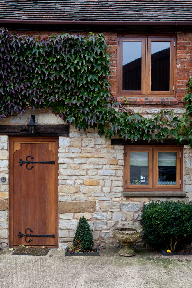 This is an example of a rural front door in West Midlands with a single front door and a medium wood front door.