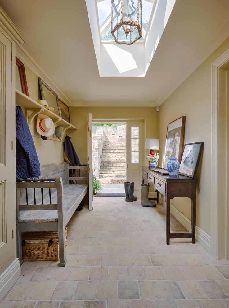 Design ideas for a country hallway in Gloucestershire with beige walls, terracotta flooring, a single front door, a white front door, beige floors and feature lighting.