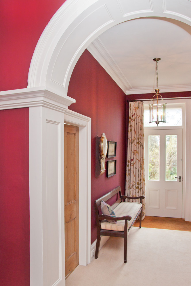 На фото: узкая прихожая среднего размера с красными стенами, паркетным полом среднего тона, одностворчатой входной дверью и белой входной дверью