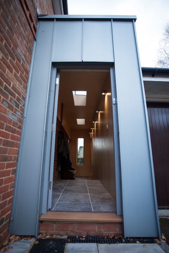 Immagine di un piccolo corridoio minimal con pavimento con piastrelle in ceramica, una porta singola, una porta grigia e pavimento grigio