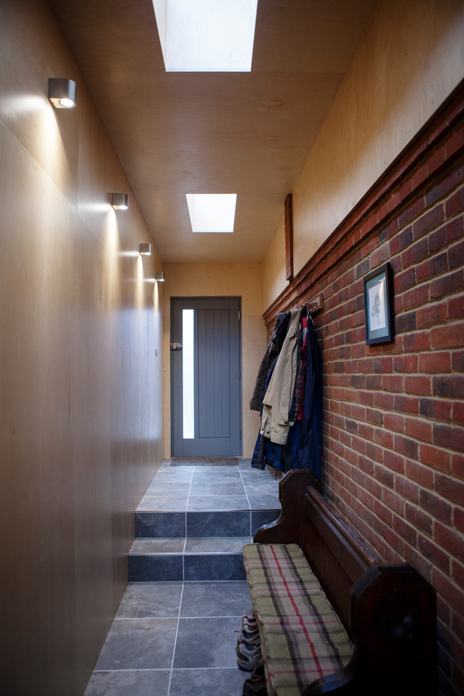 Ispirazione per un piccolo corridoio contemporaneo con pavimento con piastrelle in ceramica, una porta singola, una porta grigia e pavimento grigio