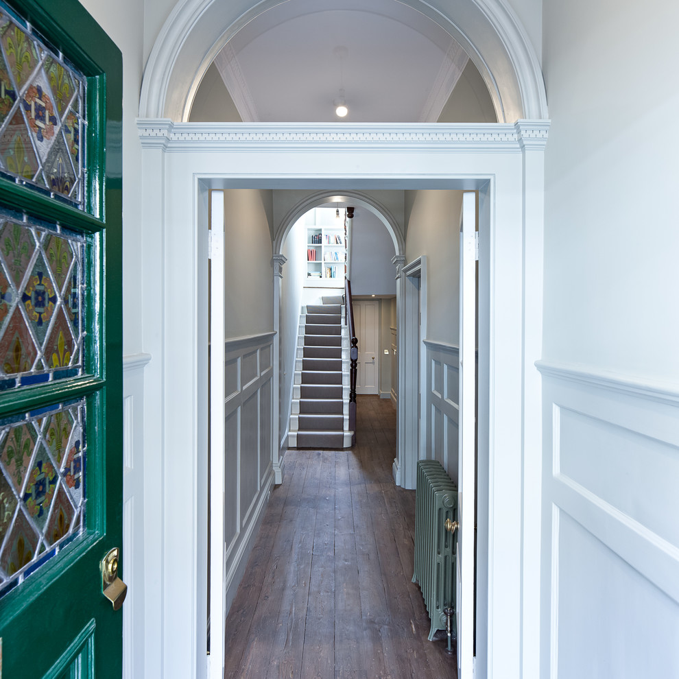 Exemple d'une entrée victorienne avec un couloir, un mur blanc, un sol en bois brun, une porte simple et une porte verte.