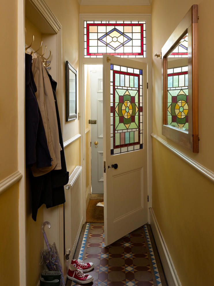 Imagen de entrada clásica con paredes amarillas, suelo de baldosas de cerámica, puerta simple y puerta azul