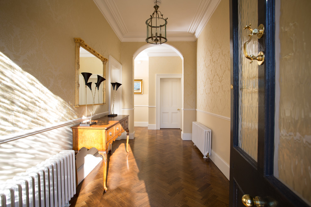 Ejemplo de hall tradicional grande con suelo de madera en tonos medios, puerta simple, paredes beige y puerta negra