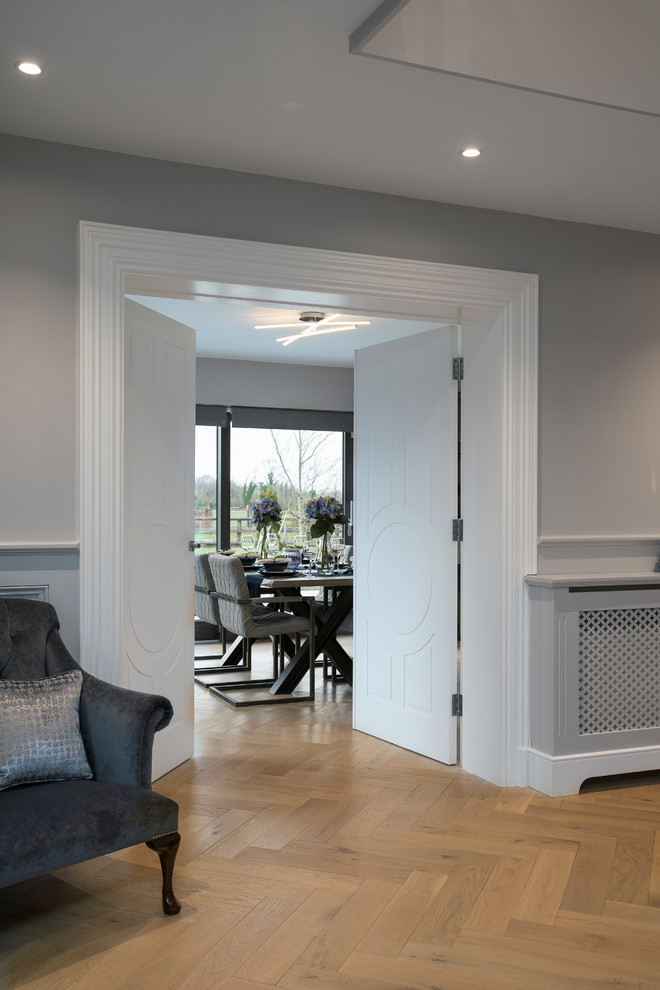 This is an example of a large contemporary hallway in Dublin with grey walls, light hardwood flooring, a single front door, a grey front door and grey floors.