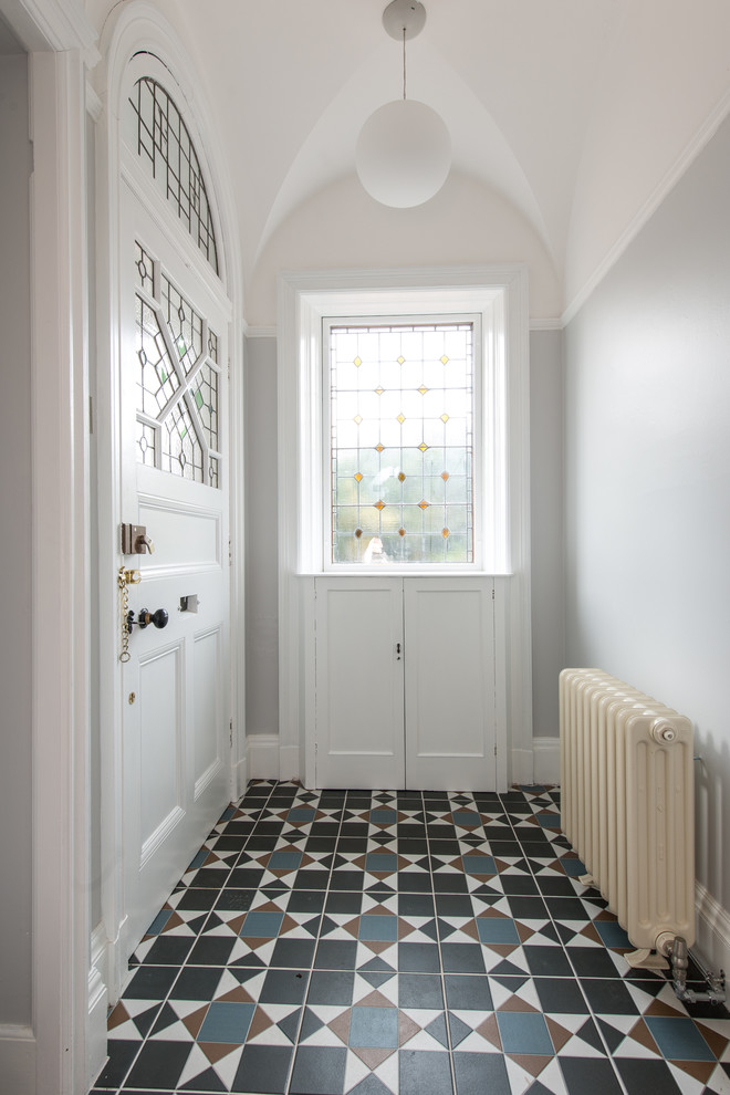 他の地域にある中くらいなヴィクトリアン調のおしゃれな玄関ラウンジ (グレーの壁、白いドア、セラミックタイルの床) の写真