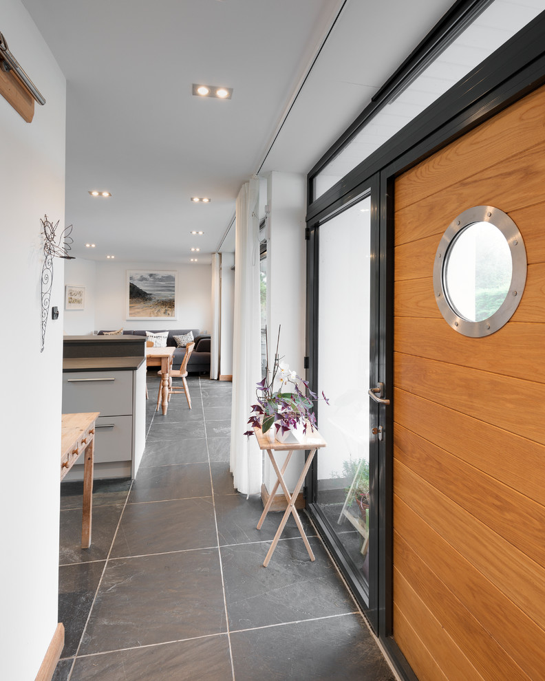 Small modern front door in Cornwall with white walls, slate flooring, a single front door, a light wood front door and grey floors.