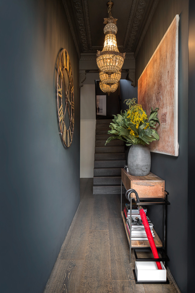 Aménagement d'une entrée éclectique de taille moyenne avec un couloir, un sol en bois brun, un sol marron et un mur noir.