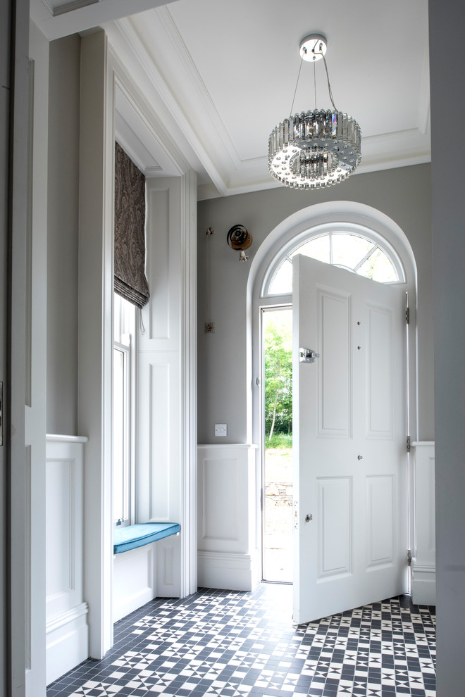 На фото: большое фойе в стиле неоклассика (современная классика) с серыми стенами, одностворчатой входной дверью, белой входной дверью и разноцветным полом с