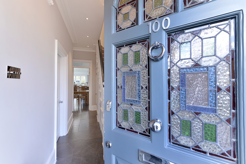 ロンドンにある中くらいなヴィクトリアン調のおしゃれな玄関ドア (白い壁、大理石の床、青いドア、黒い床) の写真
