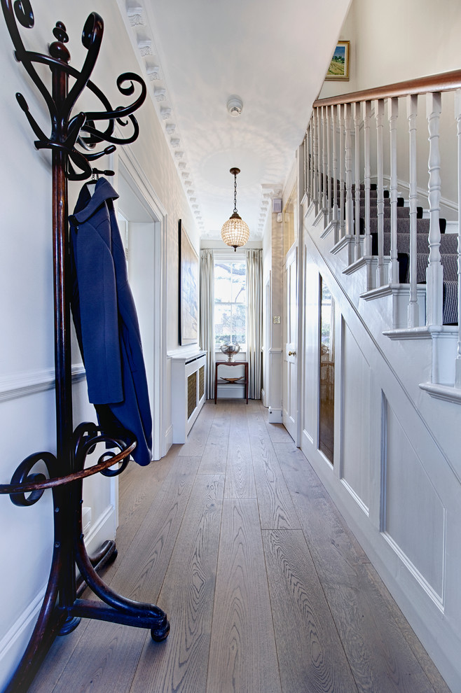 Imagen de hall tradicional de tamaño medio con paredes blancas, suelo de madera en tonos medios, puerta simple y puerta blanca