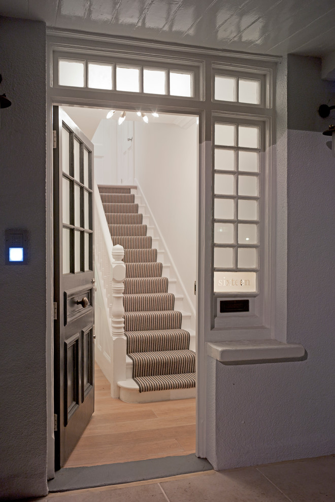 Foto di una porta d'ingresso minimal con pareti bianche, parquet chiaro, una porta singola e una porta nera