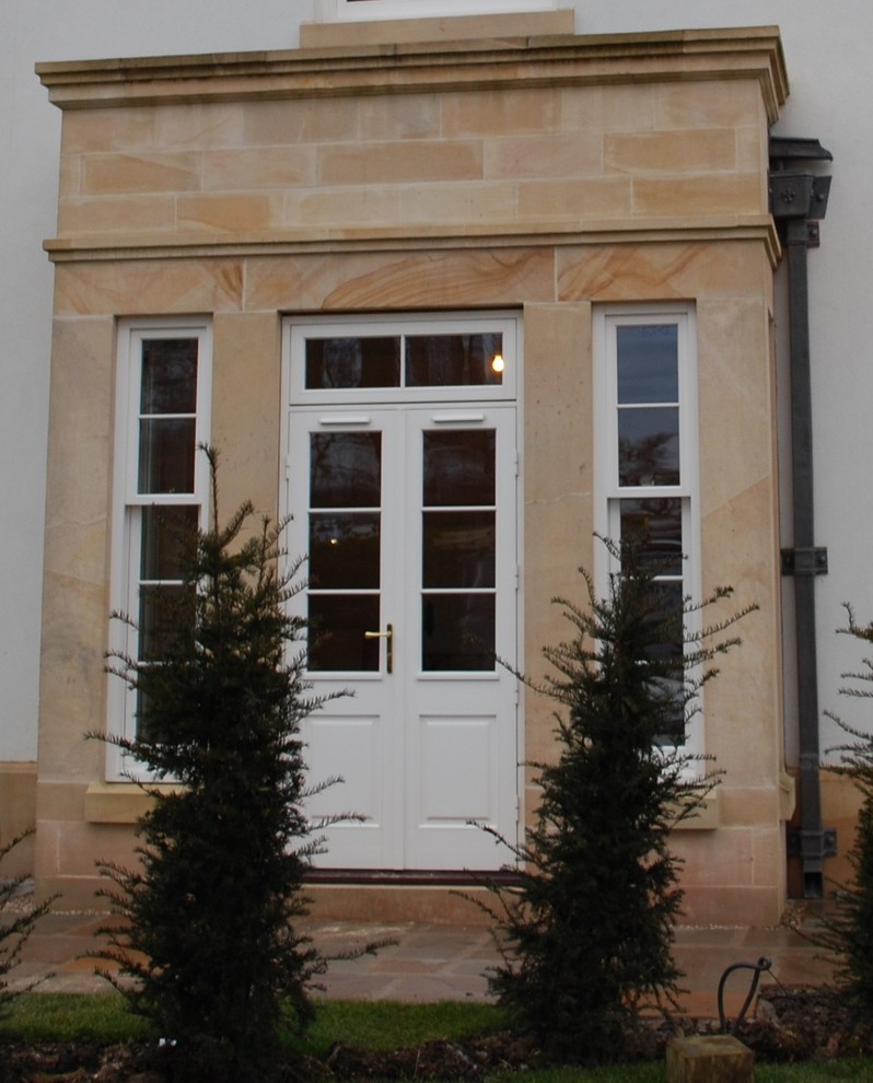 Cette image montre une porte d'entrée traditionnelle avec une porte double et une porte blanche.
