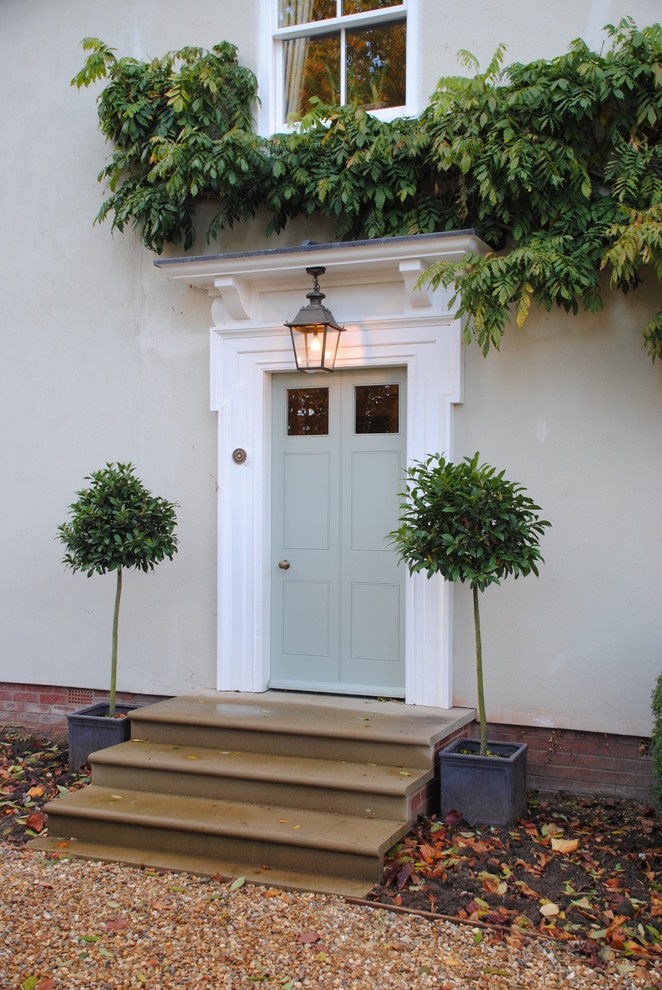 他の地域にある中くらいなトラディショナルスタイルのおしゃれな玄関ドア (ベージュの壁、ライムストーンの床、緑のドア) の写真
