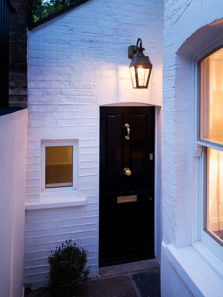 ハートフォードシャーにあるラグジュアリーな小さなおしゃれな玄関ドア (白い壁、ライムストーンの床、黒いドア) の写真