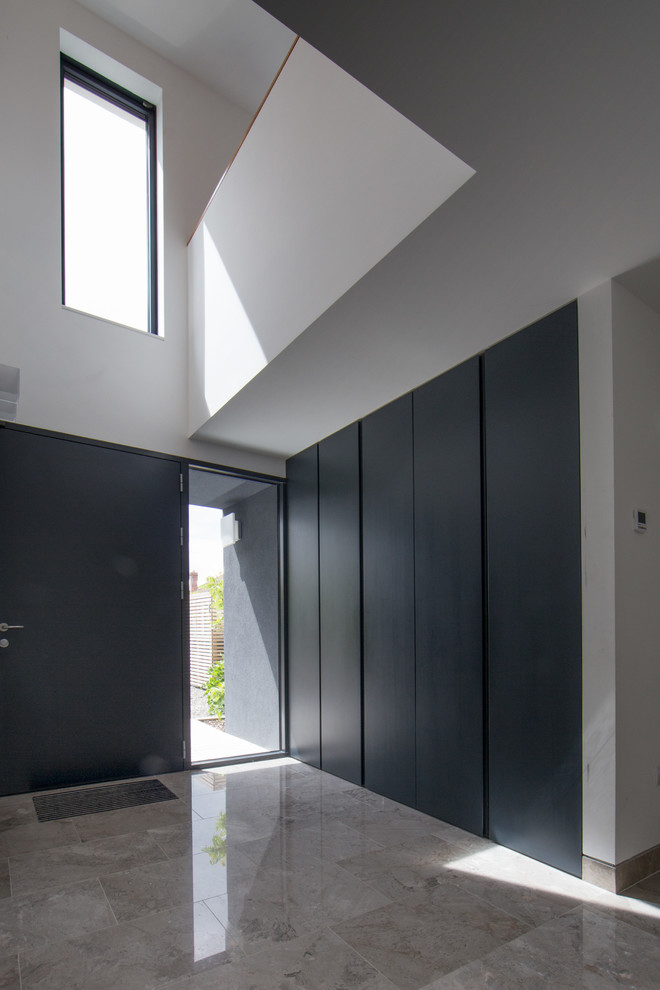 На фото: узкая прихожая среднего размера в современном стиле с белыми стенами, мраморным полом, одностворчатой входной дверью, серой входной дверью и серым полом