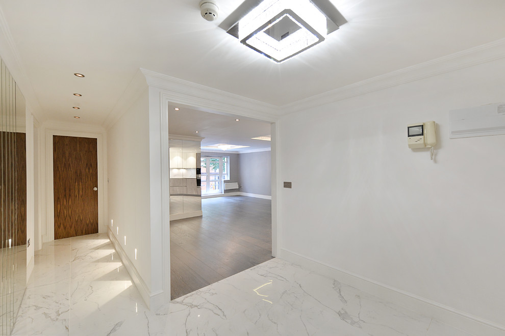 Réalisation d'une entrée de taille moyenne avec un couloir, un mur blanc, un sol en marbre, une porte simple et un sol blanc.
