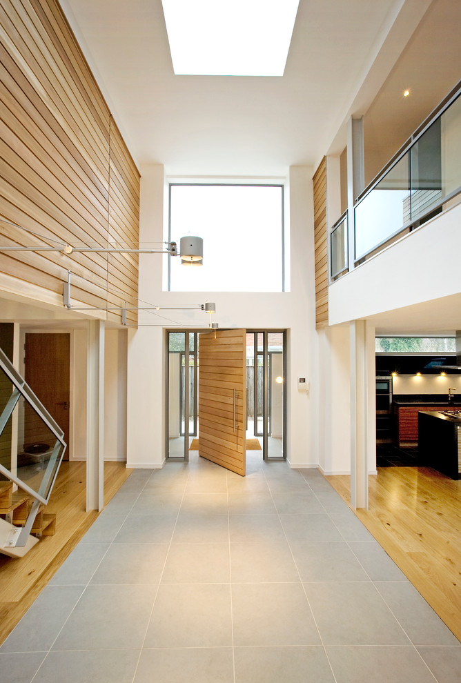 Inspiration pour un hall d'entrée design avec un mur blanc, parquet clair, une porte pivot et une porte en bois clair.