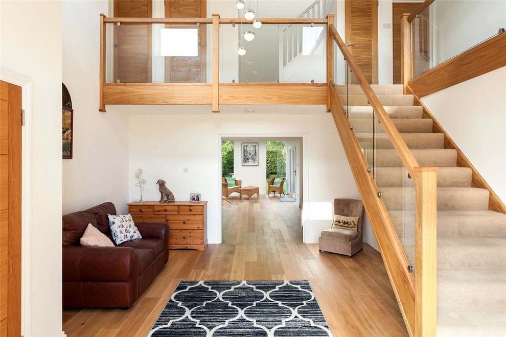 Aménagement d'un vestibule contemporain de taille moyenne avec un mur blanc, un sol en bois brun et un sol beige.