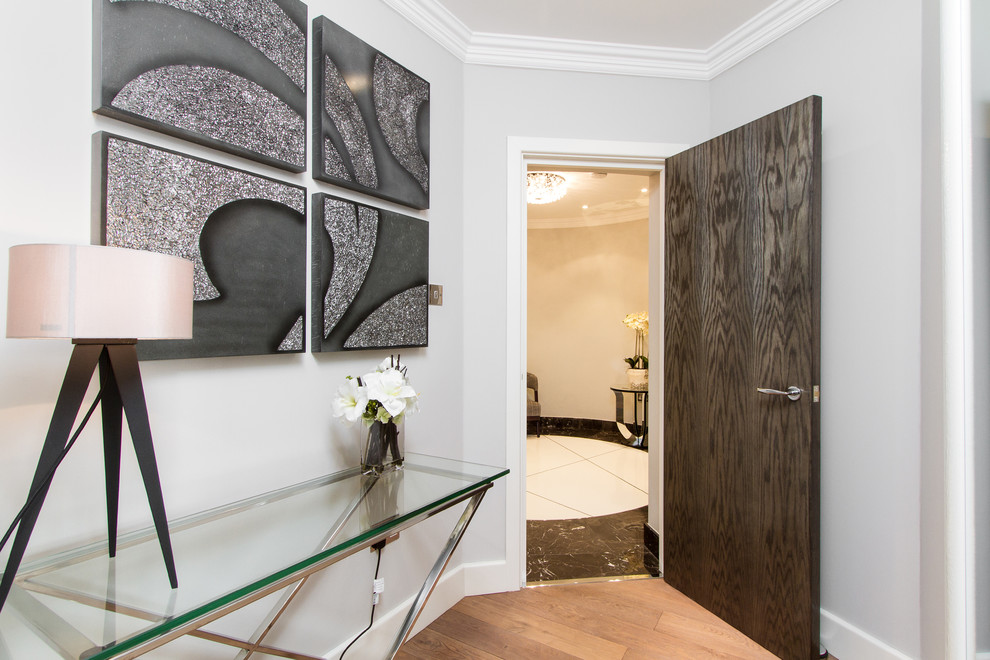 Cette image montre un hall d'entrée design avec un mur gris, une porte simple et une porte en bois foncé.