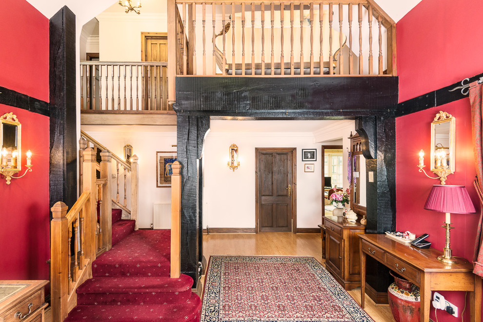 Diseño de hall tradicional grande con paredes rojas y suelo de madera en tonos medios