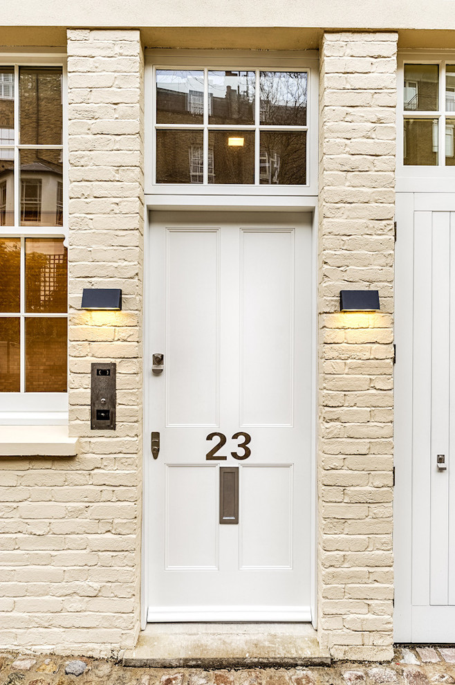 Example of a transitional entryway design in London with a white front door