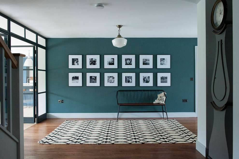 Ispirazione per un ingresso contemporaneo di medie dimensioni con pareti verdi, parquet scuro, pavimento marrone e una porta in vetro
