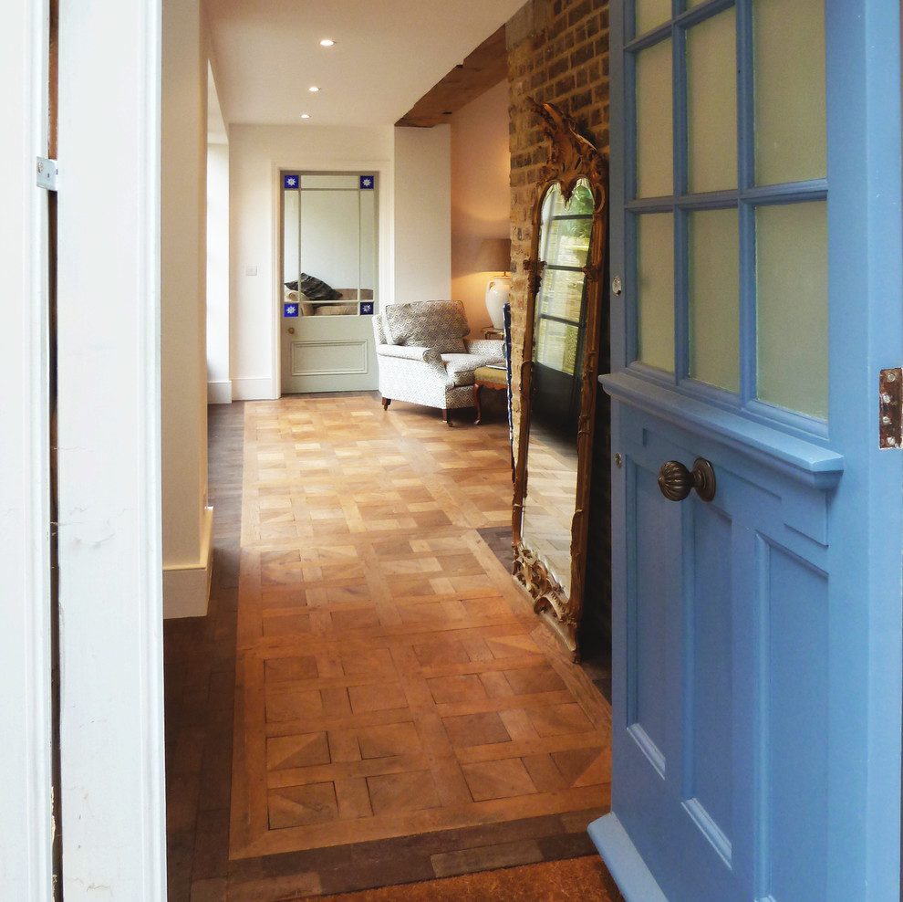 Diseño de hall rústico de tamaño medio con puerta azul, paredes blancas y suelo de madera en tonos medios