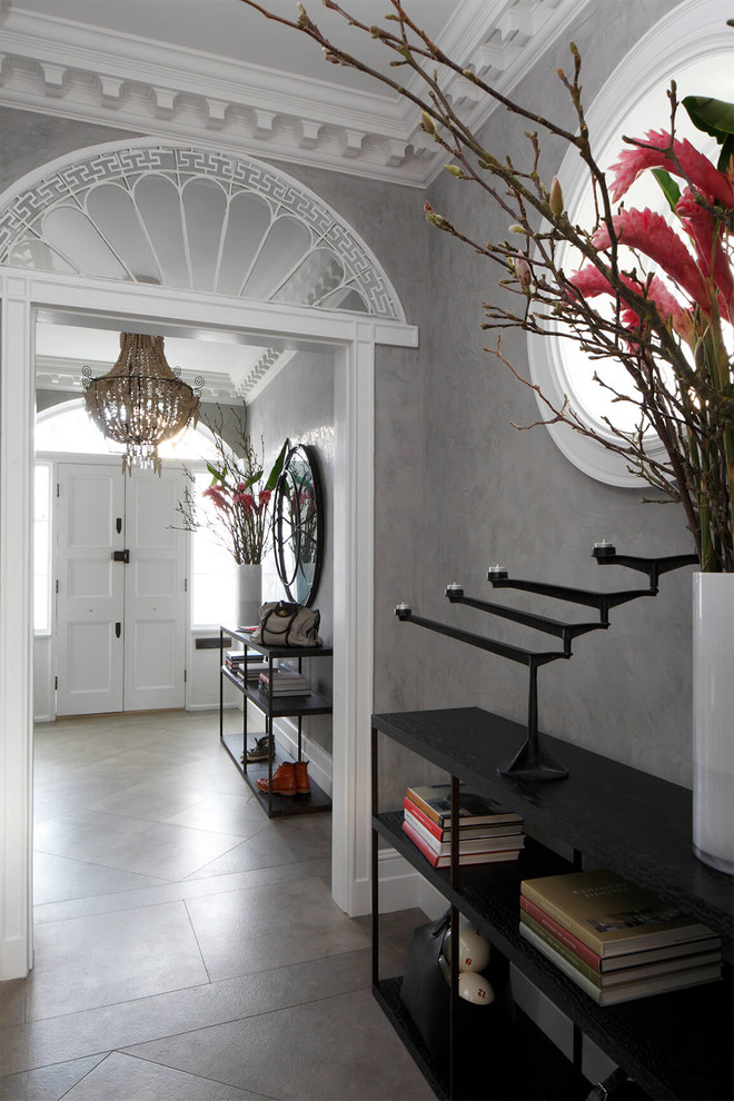 Idée de décoration pour une entrée bohème avec un couloir, un mur gris, une porte double, une porte blanche et un sol gris.