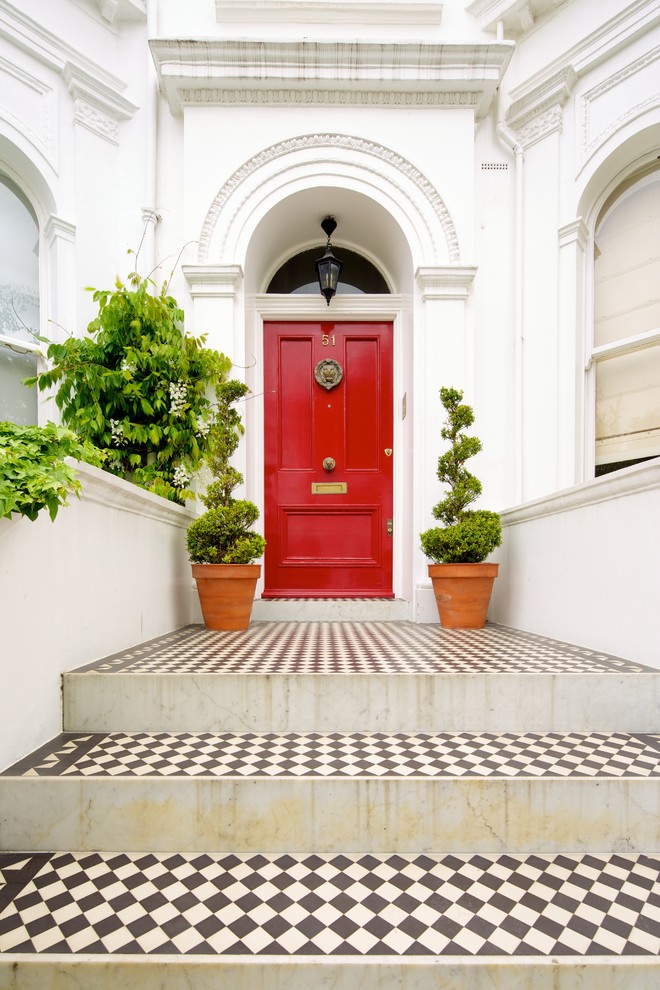 На фото: входная дверь в классическом стиле с белыми стенами, полом из керамогранита, одностворчатой входной дверью, красной входной дверью и разноцветным полом