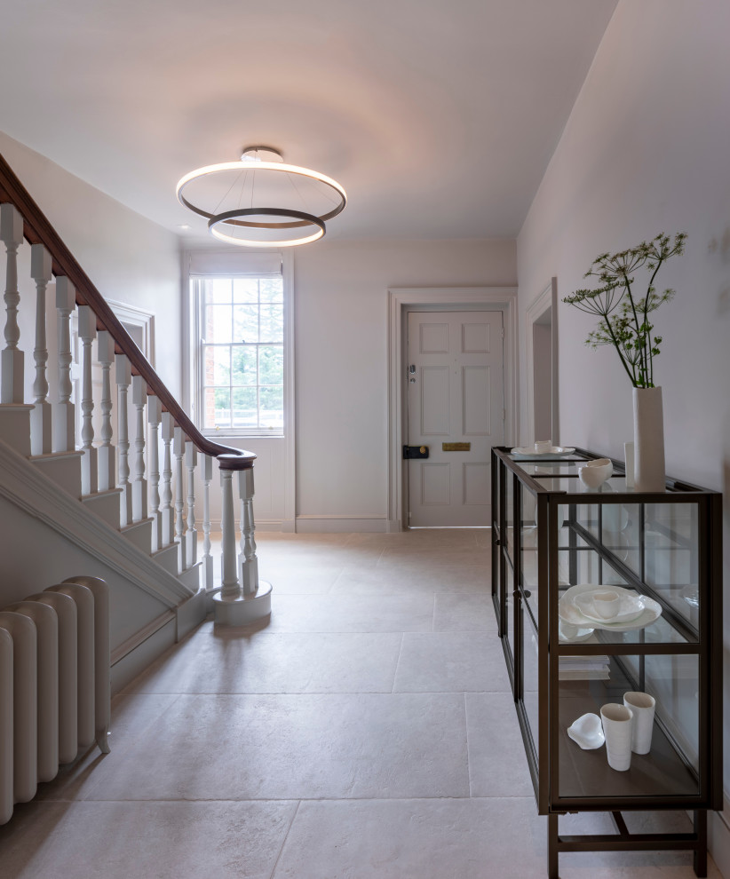 This is an example of a large contemporary hallway in Oxfordshire with white walls, ceramic flooring, a single front door, a black front door and white floors.
