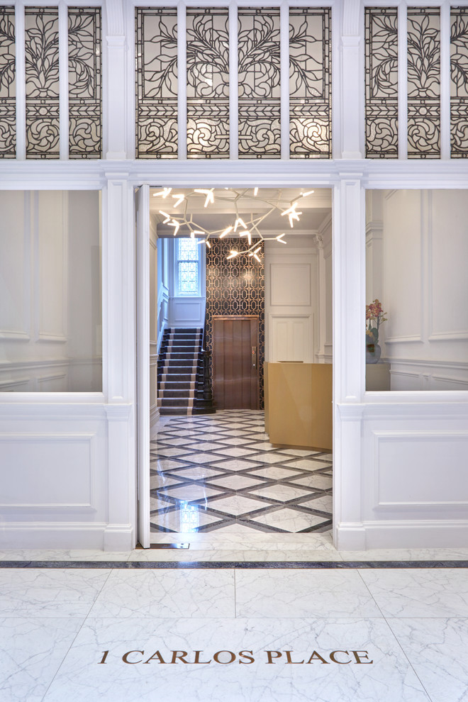 Exemple d'une très grande entrée tendance avec un sol en marbre, une porte simple, une porte blanche et un sol multicolore.