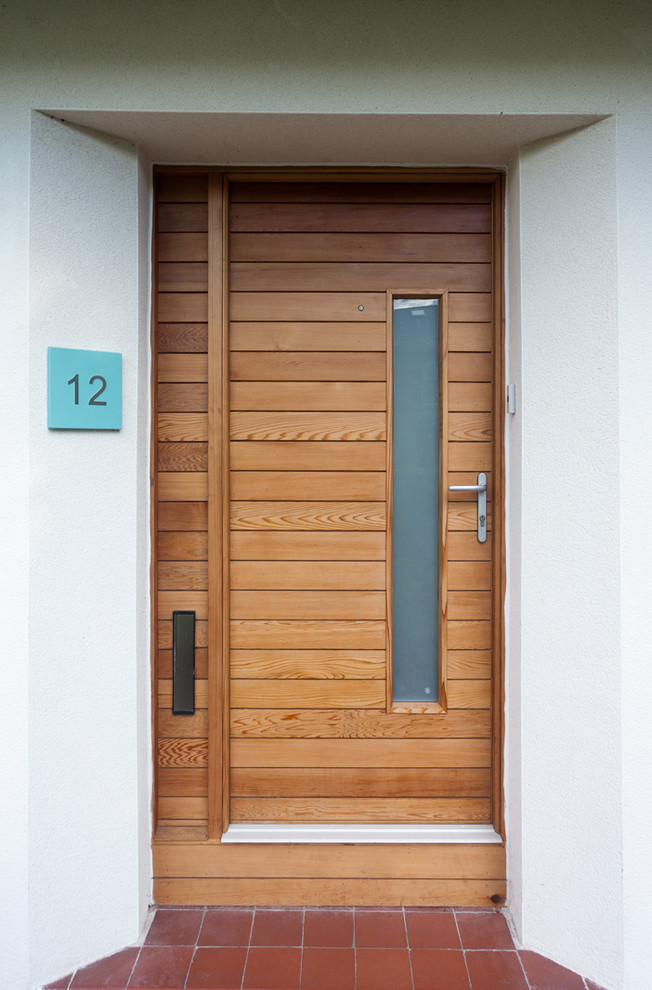 This is an example of a medium sized contemporary front door in Glasgow with white walls, terracotta flooring, a pivot front door and a medium wood front door.